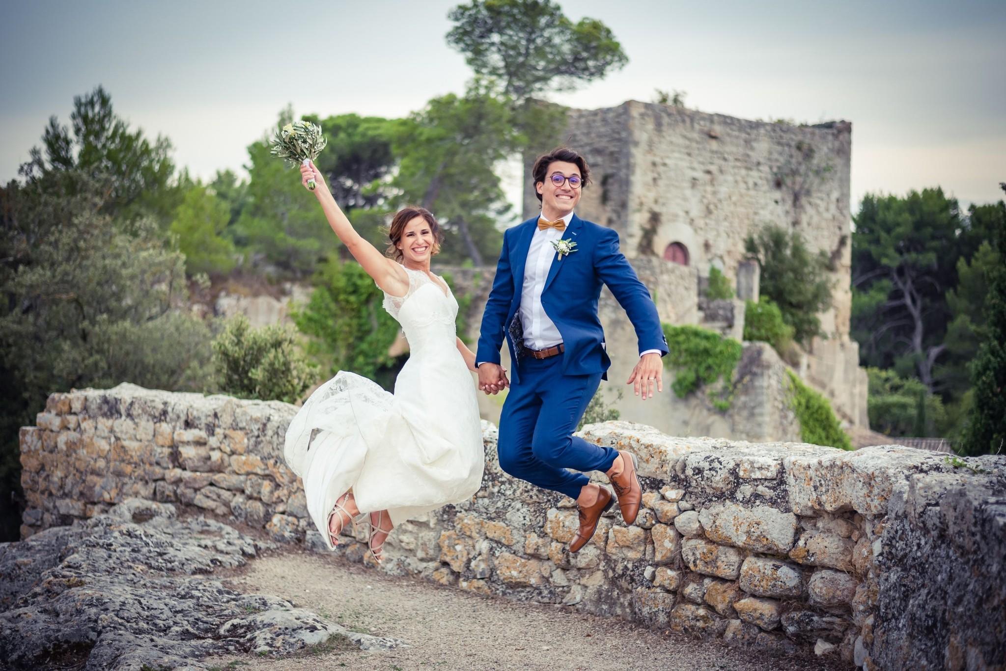 Couple de mariés sautant devant un château en Provence