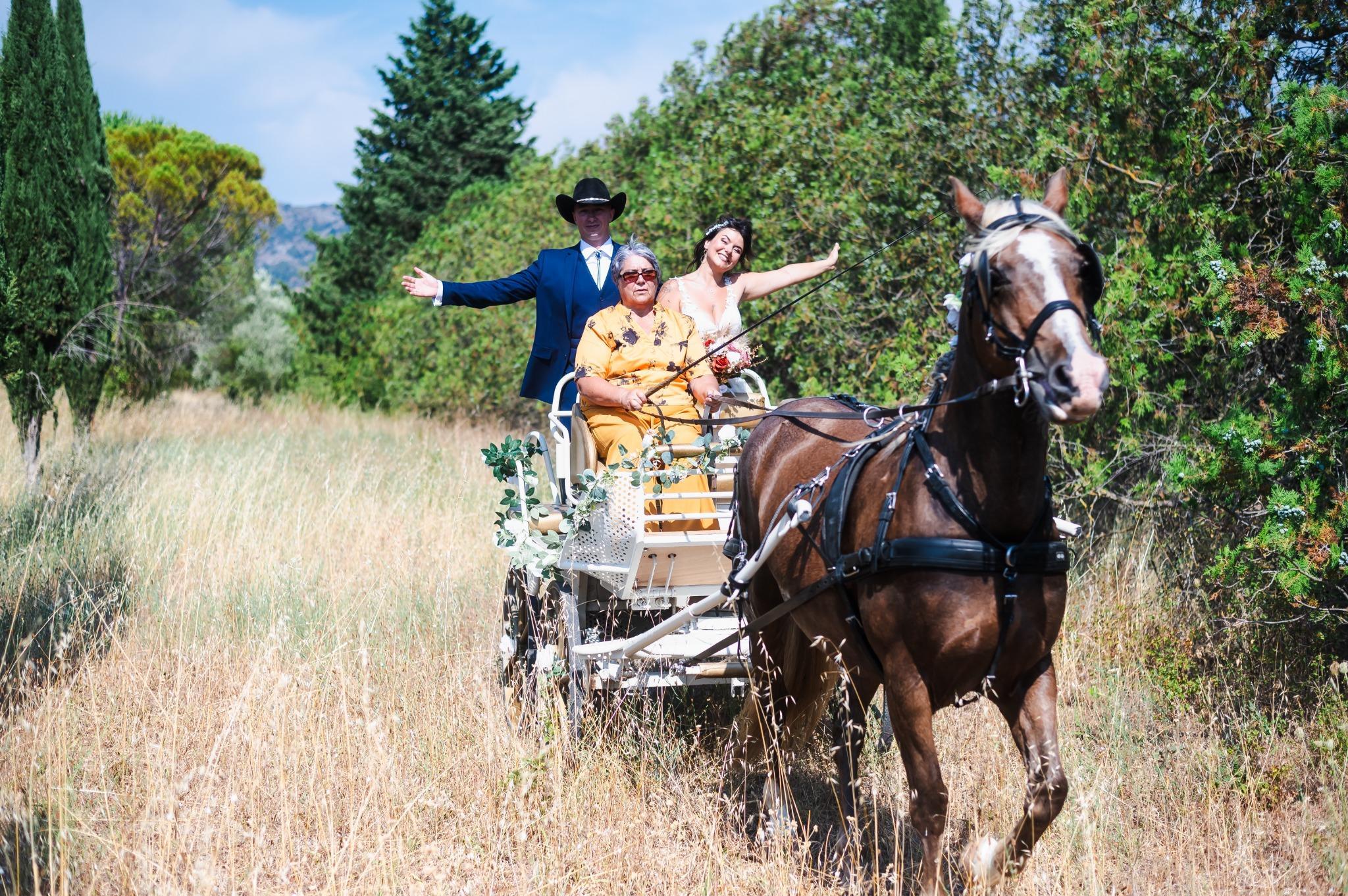 Une mariée souriante prend place dans une calèche tirée par un cheval, accompagnée de ses proches.