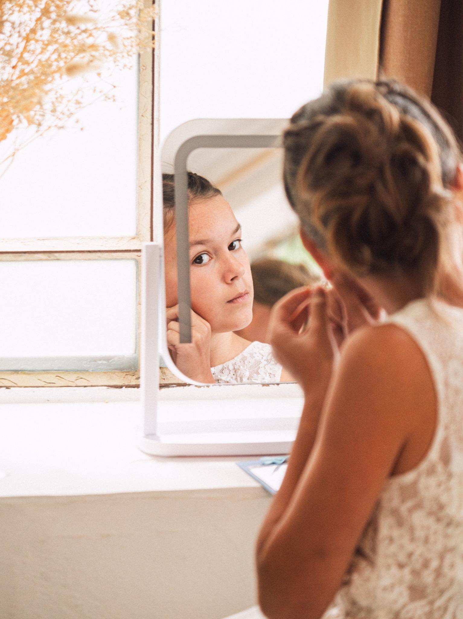 Une jeune fille se regarde dans un miroir pendant les préparatifs de la mariée.